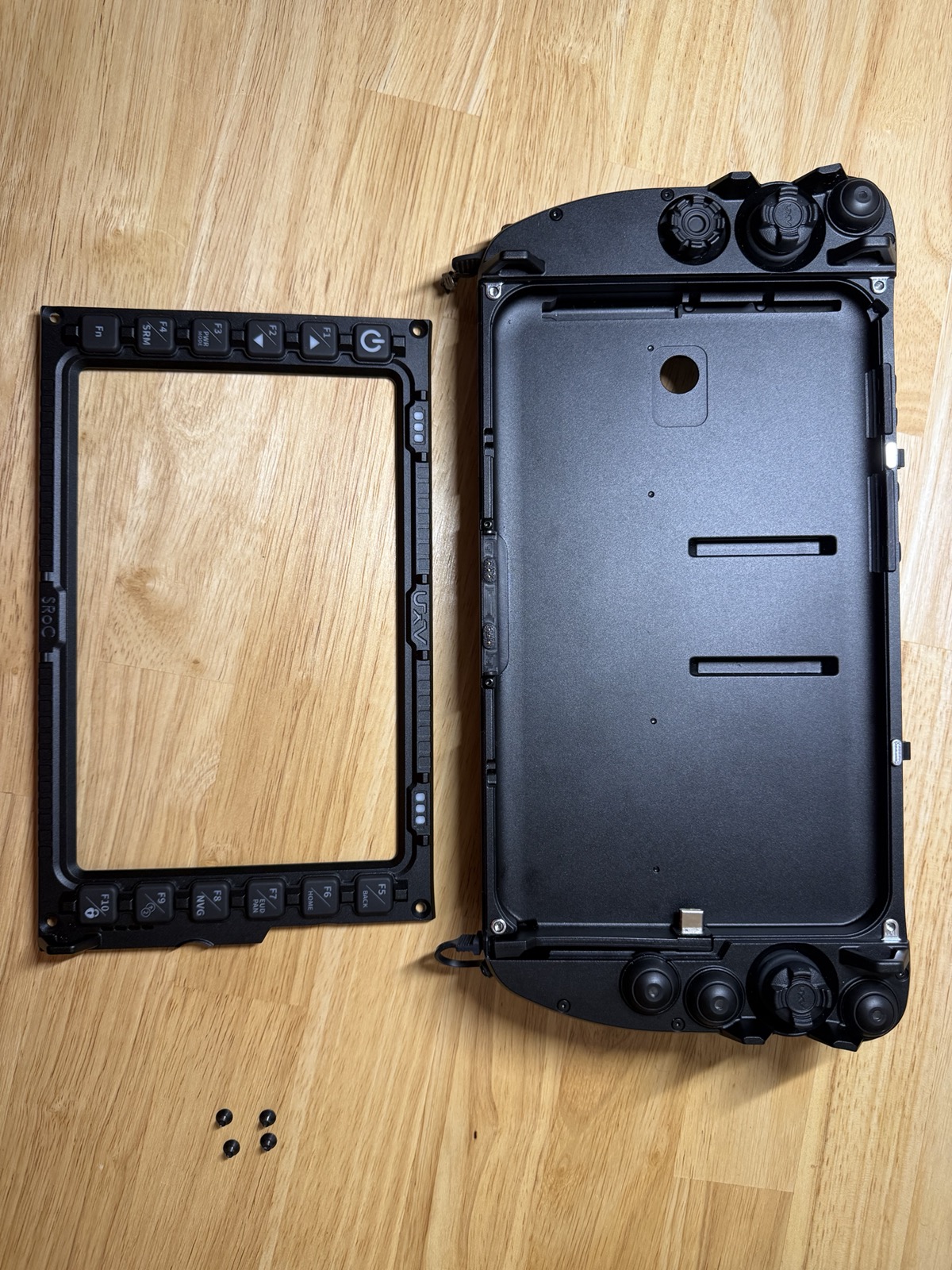 Front bezel separated from the rear shell, with the tablet cavity, USB-C dock connector, and the four removed screws laid out below