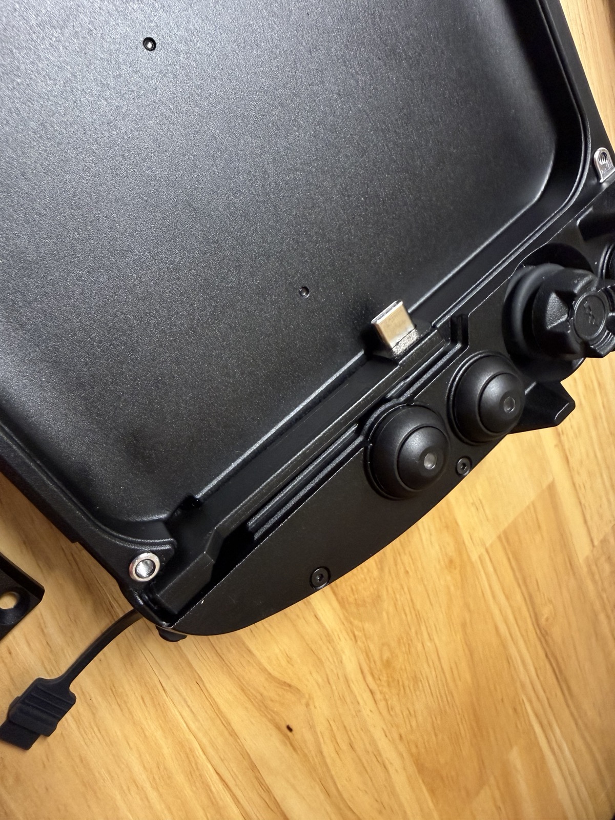 Close-up of the bottom-right corner of the housing showing the USB-C dock connector on its spring-loaded flex mount, next to the joystick controls